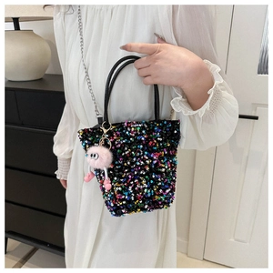 Gros plan du sac à main à paillettes colorées avec poignée en cuir et breloque en peluche