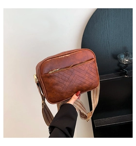 Detail of vintage brown crossbody bag with V-quilted pattern and wide woven strap