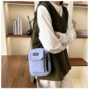 Detailed close-up of light purple nylon phone bag with fashion label and side zipper detail