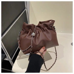 Detailed view of dark brown pleated cloud bag with silver metal chain and polished ball