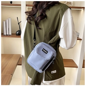 Detail of light blue nylon crossbody bag with functional flap pocket and fashion label