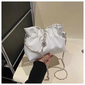 Detail of creamy white pleated bucket bag with silver chain and metal ball ornament