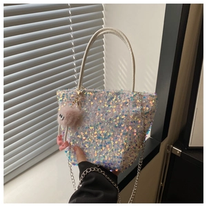 Détail du sac à main à paillettes irisées avec poignée blanche et breloque peluche
