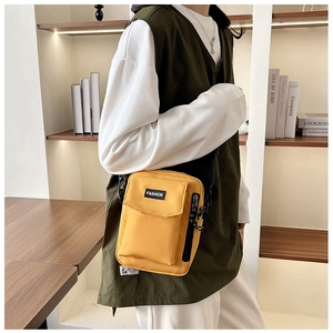 Detail of yellow nylon crossbody bag featuring fashion label and functional front pocket