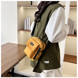 Detailed side view of a yellow nylon crossbody bag worn by a model in a cozy home setting