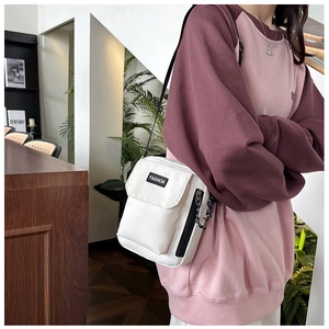 White nylon crossbody phone bag with fashion label and adjustable strap in cafe setting