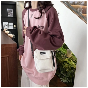 Detail view of a white nylon crossbody bag worn with a pink and burgundy raglan sweatshirt
