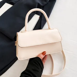 Détail d'un petit sac carré blanc crème avec poignée incurvée et bandoulière fine élégante
