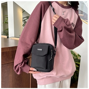 Detail of black nylon crossbody phone bag shown on model in a casual lifestyle setting
