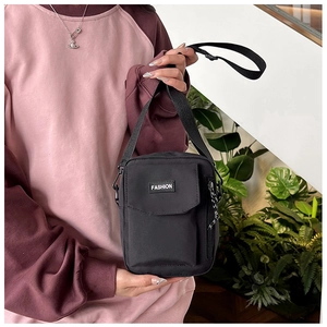 Detail of a black nylon crossbody bag with adjustable strap and front magnetic flap pocket