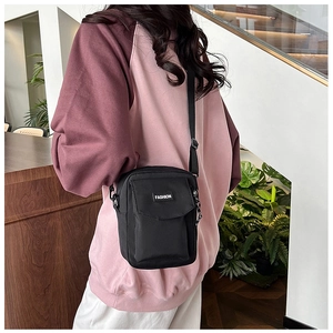 Close-up of black nylon crossbody bag featuring a front pocket and FASHION label