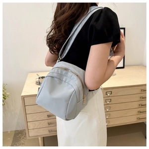 Détail d'un sac bandoulière en nylon gris-bleu clair avec fermeture éclair dorée