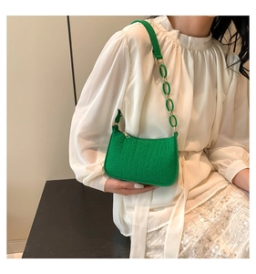 Detail of green faux-crocodile texture shoulder bag with gold acrylic chain strap