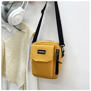 Detail of yellow nylon crossbody bag featuring black zipper and Fashion woven label