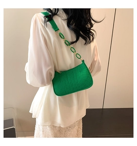 Detail view of vibrant green crocodile-patterned underarm bag with gold chain and strap
