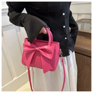 Detail of rose pink mini bag featuring a large bow knot and gold-tone metal hooks