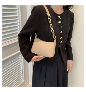 Detailed view of beige crocodile embossed crescent bag with gold chain and leather strap