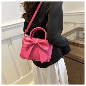 Close-up of fuchsia crossbody bag featuring a large bow and gold metal hardware