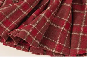 Detail of red plaid pleated skirt fabric with thick wool texture and vintage check pattern
