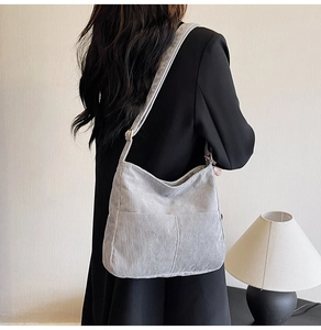 Light gray corduroy tote bag showing vertical texture and adjustable strap on a model