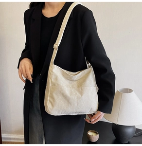 Detail of cream corduroy tote bag with metallic buckle and vertical stripe texture