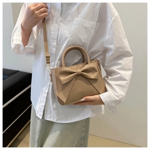 Close-up of khaki mini square bag featuring a large bow detail and adjustable strap