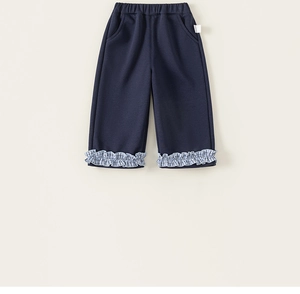 Detail of navy blue kids' trousers featuring stylish blue and white checkered ruffle hem