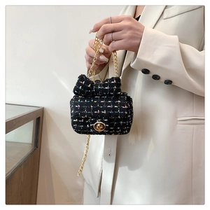 Close-up of mini tweed crossbody bag with bow detail and gold chain strap held by model