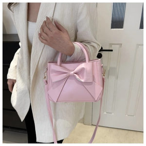 Detailed view of pink bow handbag styled with a white blazer for a chic, feminine look