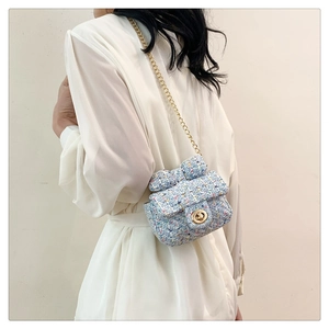 Detail of light blue tweed mini crossbody bag with golden chain and bow decoration