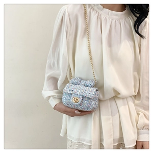 Close-up of mini tweed chain bag with blue bow decoration and golden metal clasp