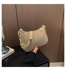 Detail of beige crocodile pattern baguette bag with chunky resin and gold chain strap