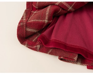 Macro detail of red plaid pleated skirt featuring premium wool fabric and smooth lining