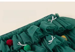 Détail de jupe en tulle vert foncé à pompons colorés et nœud pour petites filles