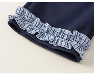 Detail of navy knit pants featuring decorative blue and white checkered ruffle trim edges