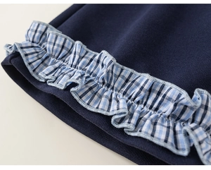 Detail of dark blue knitted sleeve cuff featuring blue and white plaid ruffle trim