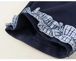 Detail of navy knit fabric showing blue and white checkered ruffle edge and fine stitching
