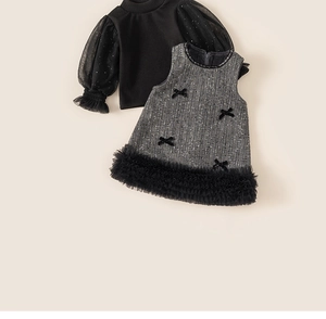 Detailed macro of girl's tweed vest dress featuring velvet bows and mesh layered lace trim