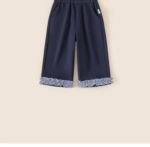 Detailed view of girls navy wide-leg trousers with checkered ruffled hem and side pockets