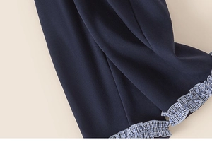 Close-up of girl's navy pants featuring blue and white checkered ruffle edge detail