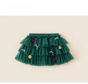Détails d'une jupe tutu en tulle vert forêt avec des pompons colorés et des nœuds blancs