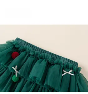 Détail de la jupe en tulle vert pour fille avec pompons rouges et couches de maille