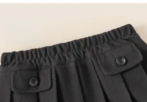 Detail view of charcoal grey pleated skirt showing elastic waist and decorative buttons