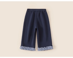 Detail of navy blue toddler trousers featuring ruffled blue and white gingham hems