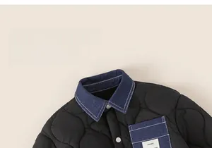 Detail of boys black quilted jacket with denim collar and white contrast buttons