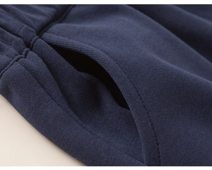 Close-up of navy blue knit trousers showing durable pocket stitching and fabric texture