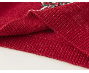 Close-up of red knitted sweater hem with festive plaid bow and ribbed cuffs detail