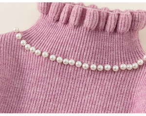 Detail of knit dress collar with ruffle edge and elegant white pearl embellishments