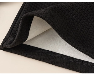 Detailed macro view of black ribbed knit fabric and thick white fleece lining for warmth