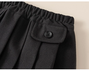 Detail of children's black pleated skirt featuring elastic waistband and flap pocket